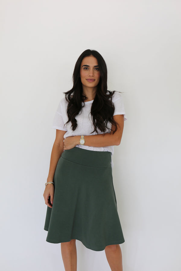 Front facing model wearing a knee length spandex circle skirt in forest green
