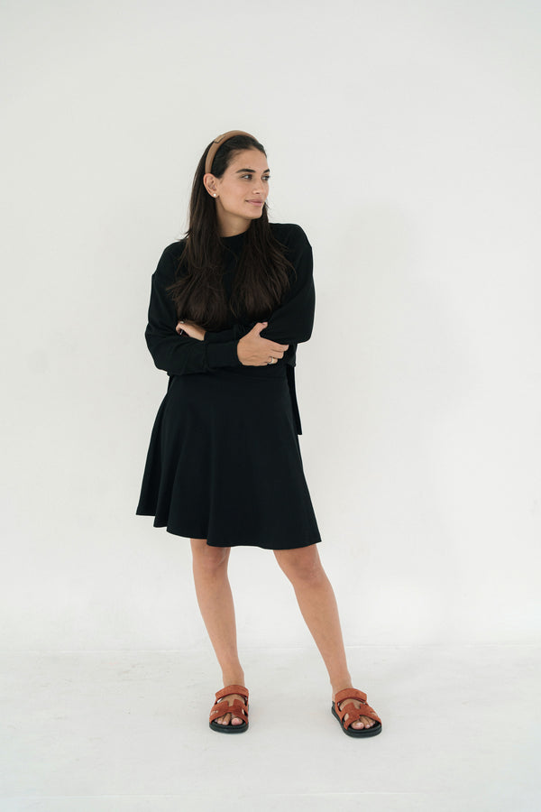 Woman wearing a skirt and matching top standing against a white background