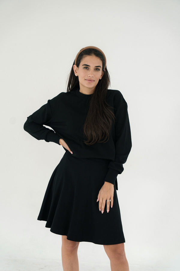 Woman wearing a black skirt with matching top against a white background