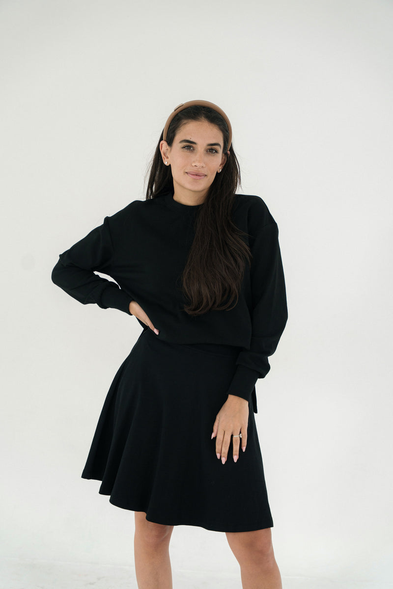 Woman wearing a black skirt with matching top against a white background
