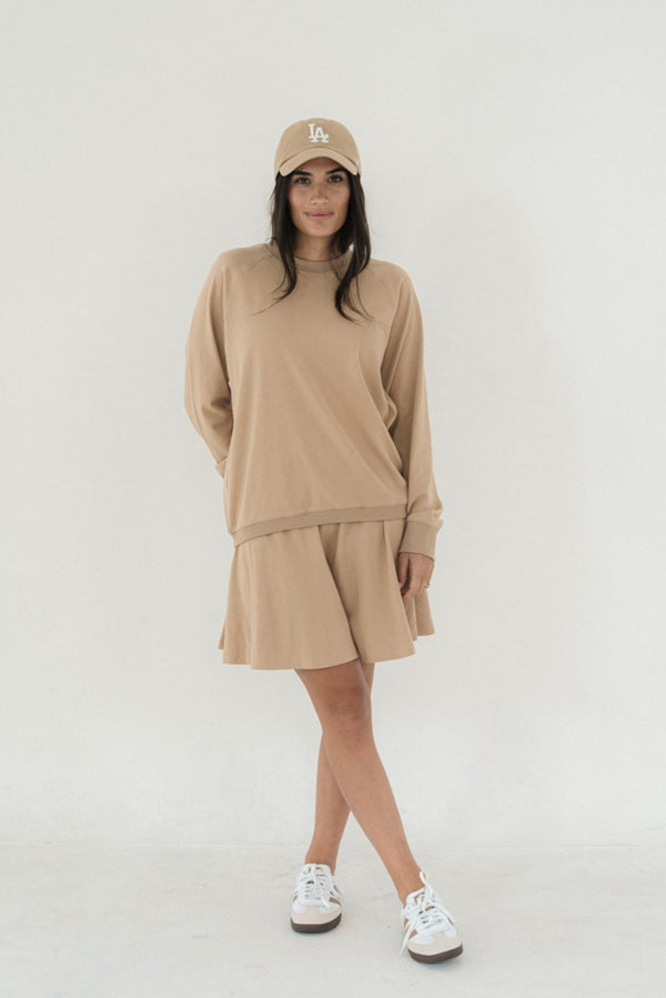 Woman wearing a beige outfit with a cap on a white background