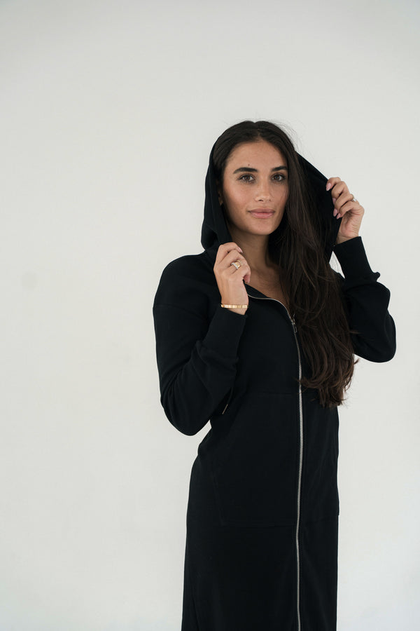 Woman wearing a black hoodie dress against a white background