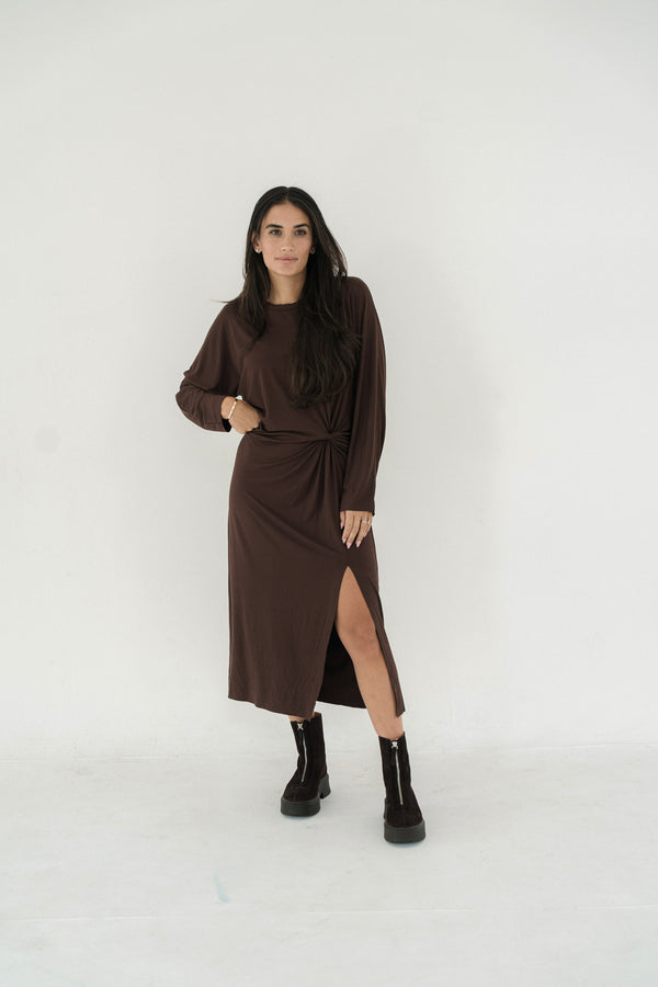 Woman wearing a brown dress with a slit on a white background