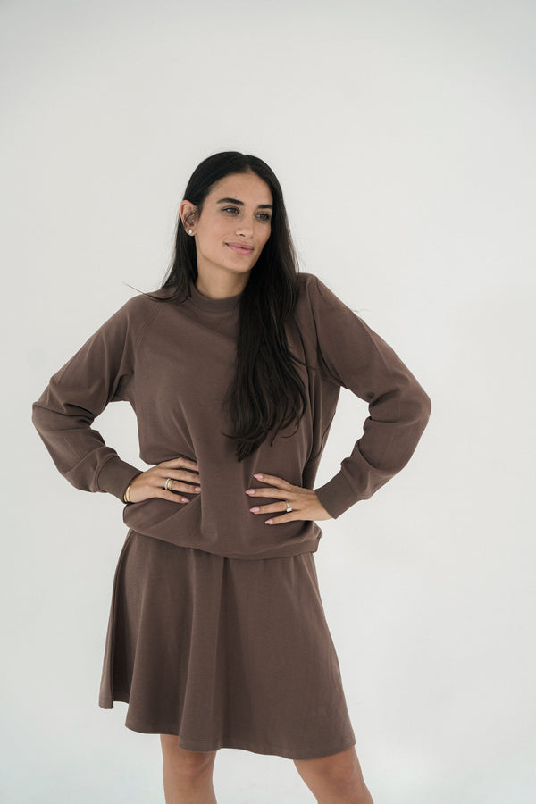 Woman wearing a brown dress against a white background