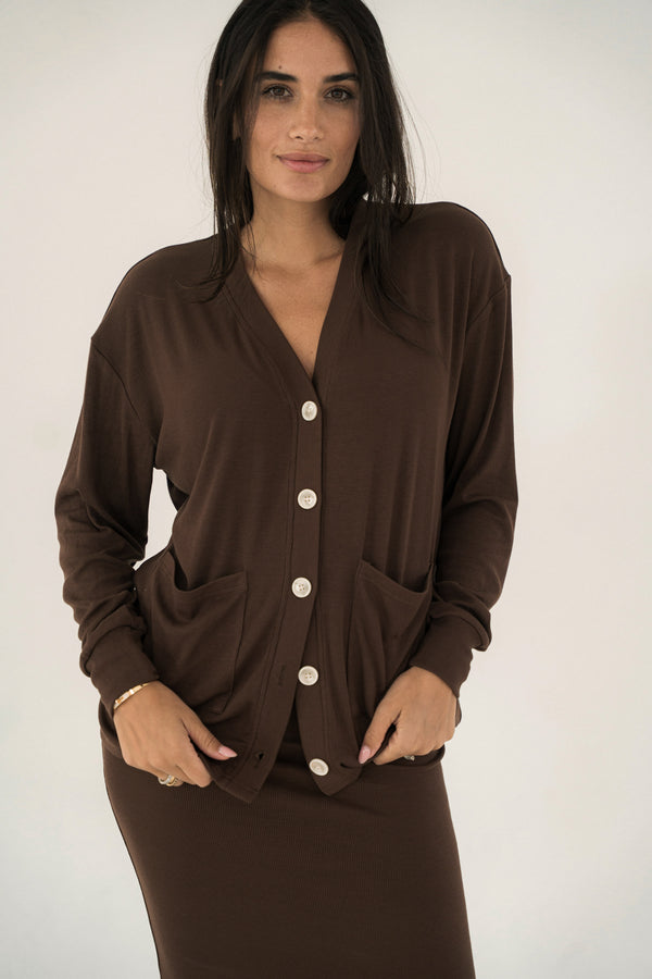 Woman wearing a brown cardigan with button details on a white background