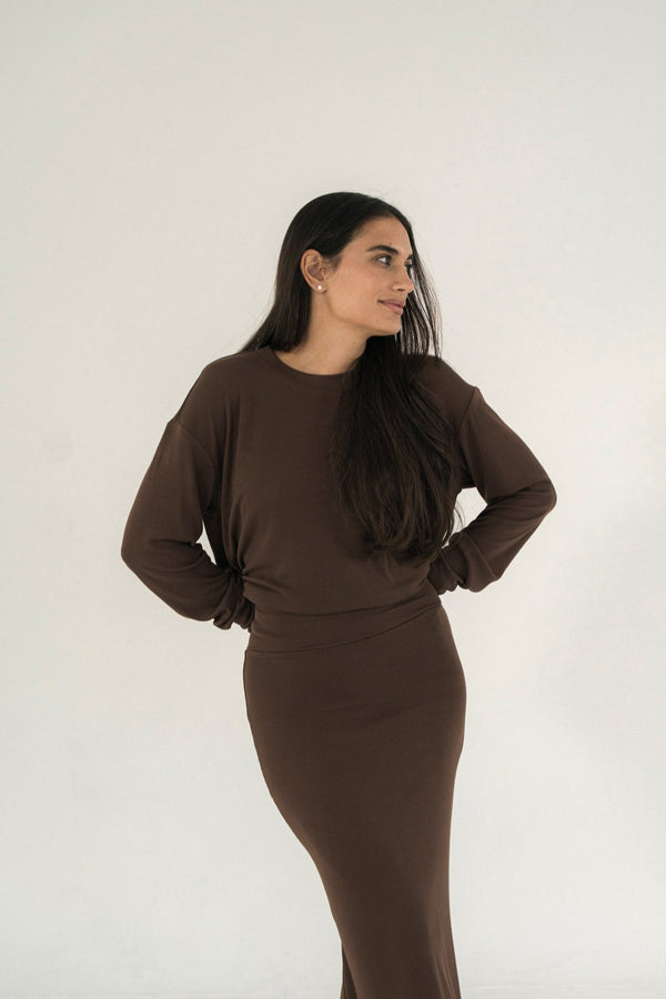 Woman wearing a matching brown top and skirt against a white background