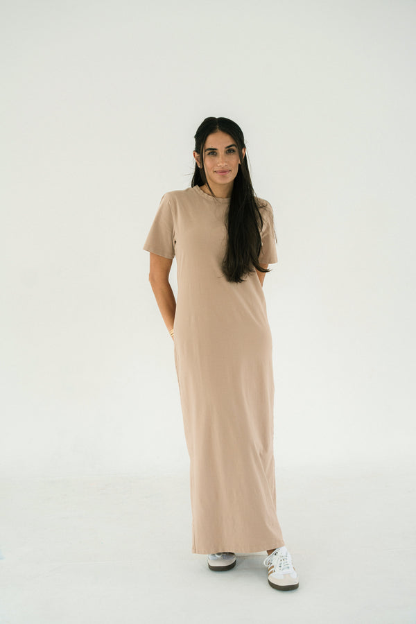 Woman wearing a long beige dress on a white background