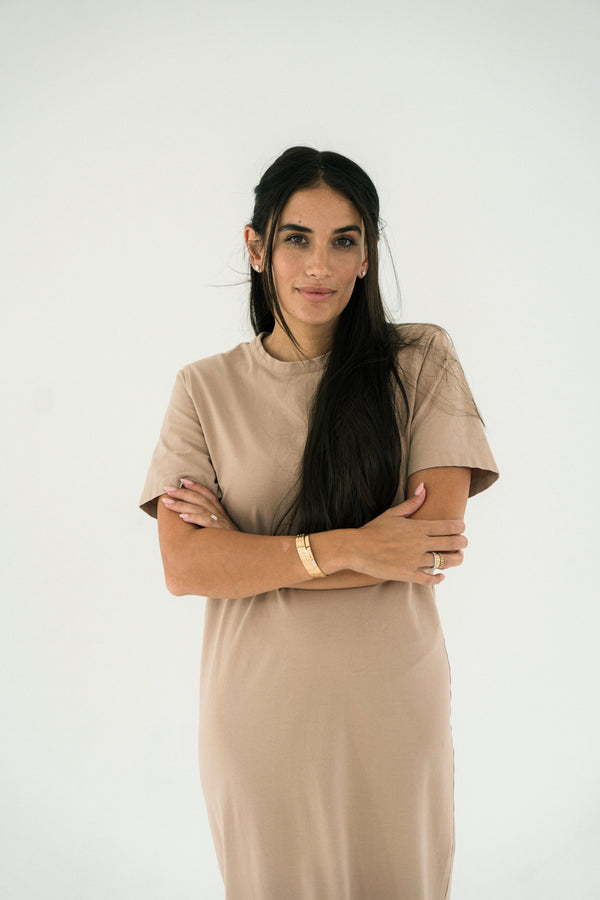 Woman wearing a beige dress with a plain white background